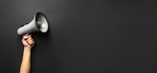A hand holding a megaphone against a sleek black background, symbolizing voice amplification and the power of communication. The image captures the essence of an announcement or call to attention