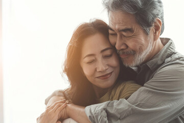 A tender hug as an Asian couple holds each other lovingly on a white background.