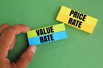 hand holding colored paper with the words value rate and price rate. Price vs Value.
