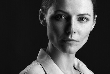 A beautiful red-haired girl with freckles in a shirt posing in the studio . grain effect used