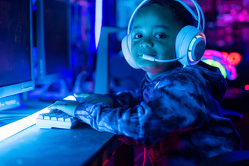 African boy wearing headphones shows smiling and looking at camera after finishing playing video...