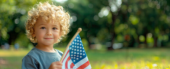 On sunny summer day, outdoors, a young boy celebrates US Independence Day, the 4th of July, holding the American flag aloft. He radiates pride as a patriotic American child with his nation's emblem