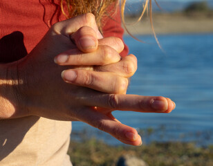 Woman's hands doing a mudra in nature with a lake behind