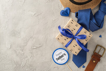 A festive arrangement for Father's Day featuring a straw hat, gift box with a blue ribbon, polka...