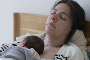 A serene moment of a mother sleeping with her newborn baby resting on her chest. The baby, dressed...
