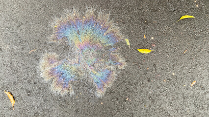 Leakage of oil or gasoline on the asphalt. Colorful gasoline fuel stain, gas spill spot or rainbow oil slick on a wet city asphalt road.