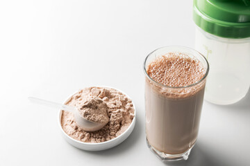 Protein drink cocktail in a glass and whey protein powder in a measuring scoop