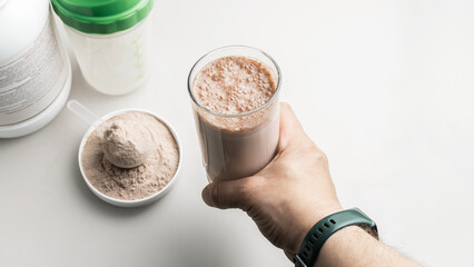 Male hand holding a protein drink cocktail in a glass