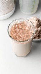Protein drink cocktail in a glass and whey protein powder in a measuring scoop
