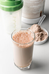Protein drink cocktail in a glass and whey protein powder in a measuring scoop