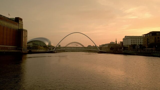 NEWCASTLE/UK 6th SEPTEMBER 2023: Drone rises from River Tyne to reveal Millennium Bridge, Sage Centre and Newcastle skyline during sunset 
