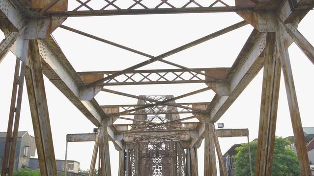 Vintage steel train bridge at Long Bien railway through a river in Downtown Hanoi, Vietnam. Urban city town.