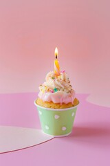 A delicious cupcake topped with a glowing candle on a soft pink background