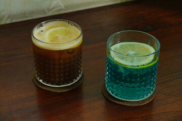 citrus coffee side by side with blue tonic water and apple juice with sliced lemon, served with...