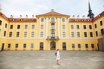 girl in a white dress, beige boots and a beige hat near Moritzburg Castle
