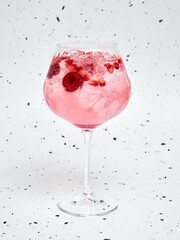 Close-up of Refreshing Pink Gin Tonic with Berries against a speckled background