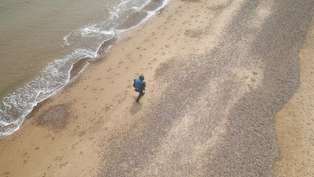 Aerial view of a tourist with backpack walking on Kessingland Beach in Suffolk, England.