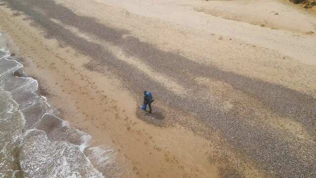A tourist man with backpack exploring the Kessingland Beach duirng sunny day in Suffolk, England.