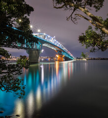 Auckland Harbour Bridge lit up in green and blue lights.