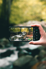 Shooting landscape video of the nature with the beautiful trees and river during spring. Using one hand to hold a phone.