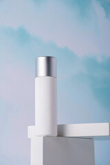 Cosmetic pink bottle, bottle, lotion or serum with stylish props on sky background.
