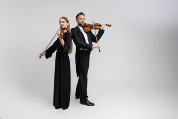 Bearded man and young woman violinist playing classical music at concert