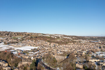 Obraz premium Aerial drone photo of the village of Golcar in West Yorkshire, England, Huddersfield in the UK showing the residential houses estates in the winter time with small patches of snow on the ground.