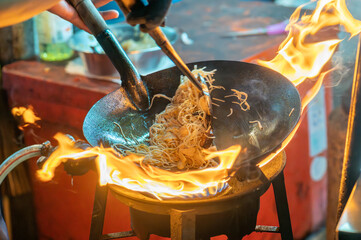 fried noodles cook in pan with big fire flame is hong kong style. Pad Thai favorite and famous...