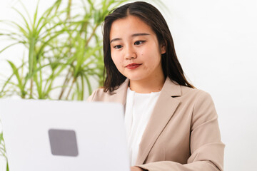 ビジネススーツを着てラップトップを操作している若い女性　ビジネスイメージ