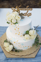 Beautiful wedding cake on an outdoor table. Cake topper with text Our Wedding written in Spanish.