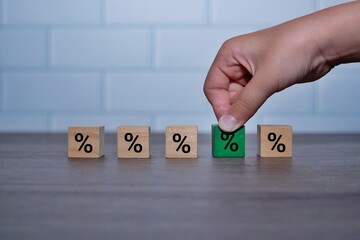Hand pick green wooden cubes with percentage icon. Choose the good interest rate for financial loan...