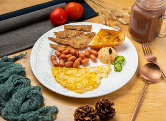 Pan fried pork chop set with omelette, beans, bread, cherry tomato, spoon and fork served in dish isolated on wooden table side view of taiwan food