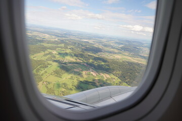 View of Green Fields From Airplane Window During Daytime Flight Over Countryside