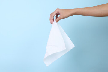 Woman hand holding paper tissue on blue background