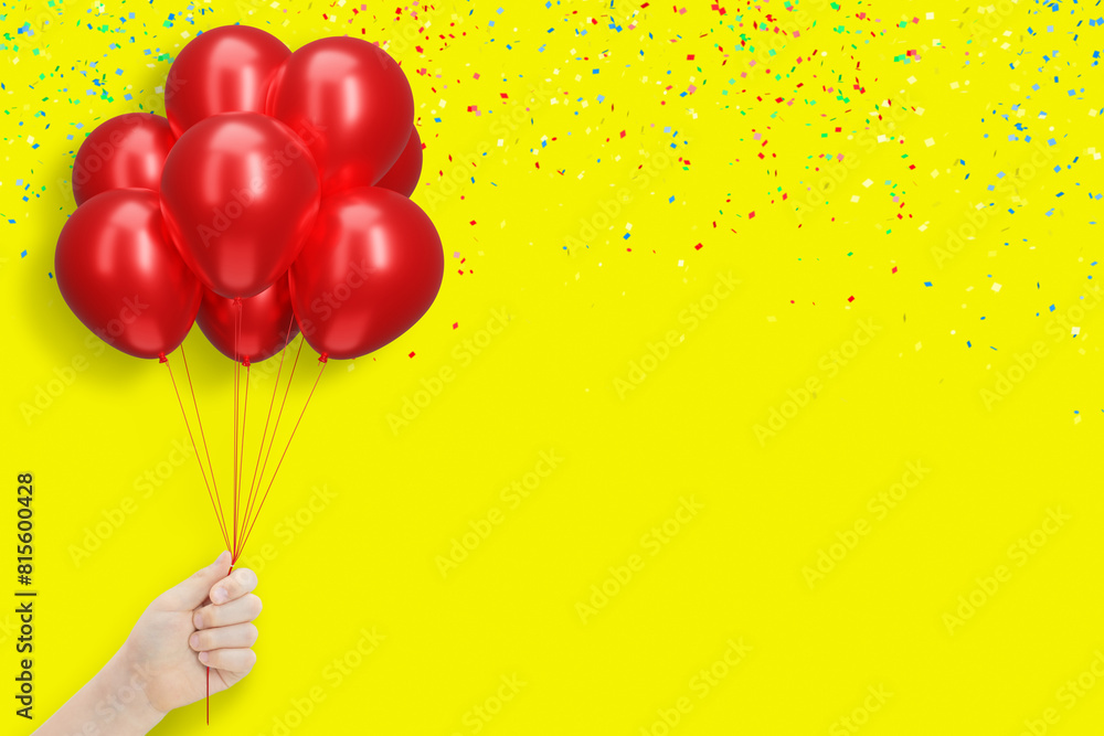 Poster female hand holding bunch of shiny red balloons on yellow background with confetti. empty space for 