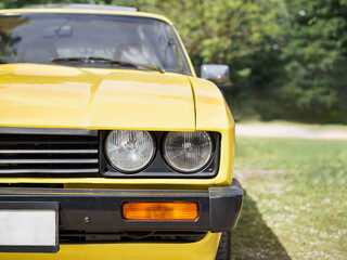 Front view of a yellow vintage car headlights. Classic car. Oldtimer. Parking in the grass. Sunny...