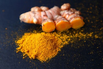 Turmeric powder and saffron or Curcuma longa Linn on a dark background.
