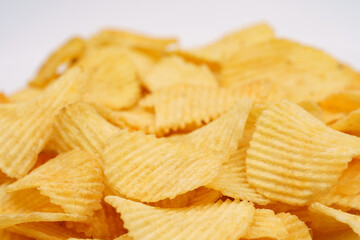 Crispy potato chips in macro. Golden fried potatoes close up. Potato snack for unhealthy fast food. 
