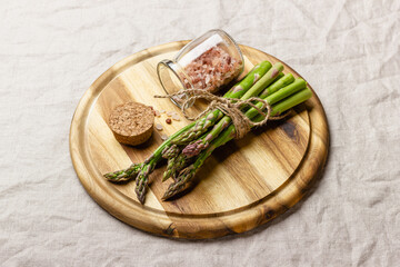 Green asparagus with pink salt on a wooden cutting board