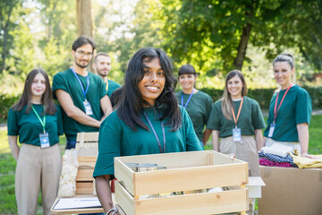 Portrait of a young woman with a group of uniformed volunteers behind her during a food bank...
