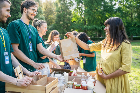 Group of volunteers prepares and delivers basic necessities to people in difficulty - Food bank, pregnant woman collects a bag