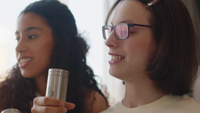Medium closeup of positive diverse teenage girls having fun singing karaoke at home. One of girls having cerebral palsy