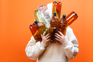 Garbage Concepts. European Female Teenager Girl Holding Plastic Empty Colorful Bottles Depicting Against Pollution Over Orange Color Background.