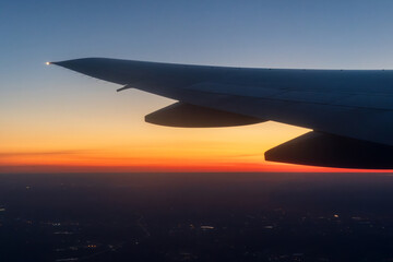 Sunset view from a flying airplane. Beautiful evening aerial landscape. View of an airplane wing....