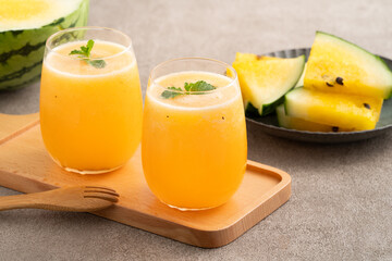 Fresh yellow watermelon juice in a glass cup on gray table background.