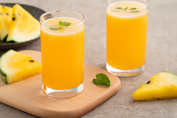 Fresh yellow watermelon juice in a glass cup on gray table background.