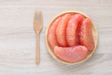 Pompelmoes,Fresh red pomelo fruit in a bowl on wooden background, (Tubtim Siam Pomelo)