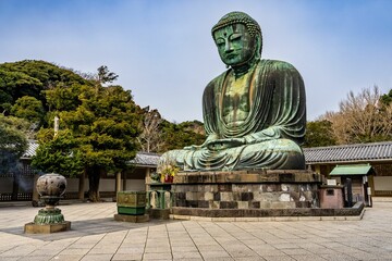 a buddha statue sitting at the base of a pagoda in front of trees