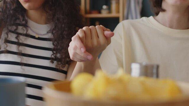 Waist up of two happy multiethnic teenage girls holding hands land singing at home. One of girls with cerebral palsy