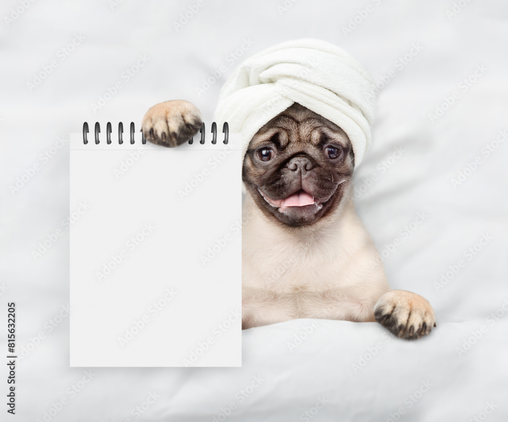 Aufkleber funny pug puppy with towel on it head relaxing on the bed at home and showing empty list. top down v